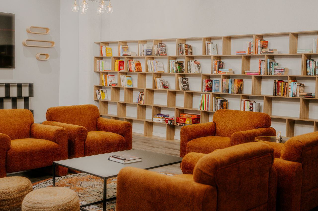 Library and lounge area with orange armchairs and bookshelf wall